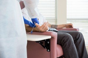 Nurse Adjusting IV Drip On Patient's Hand In Chemo Room
