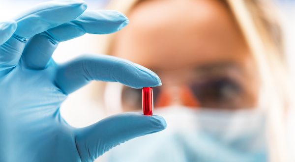 female scientist holds supplement pill